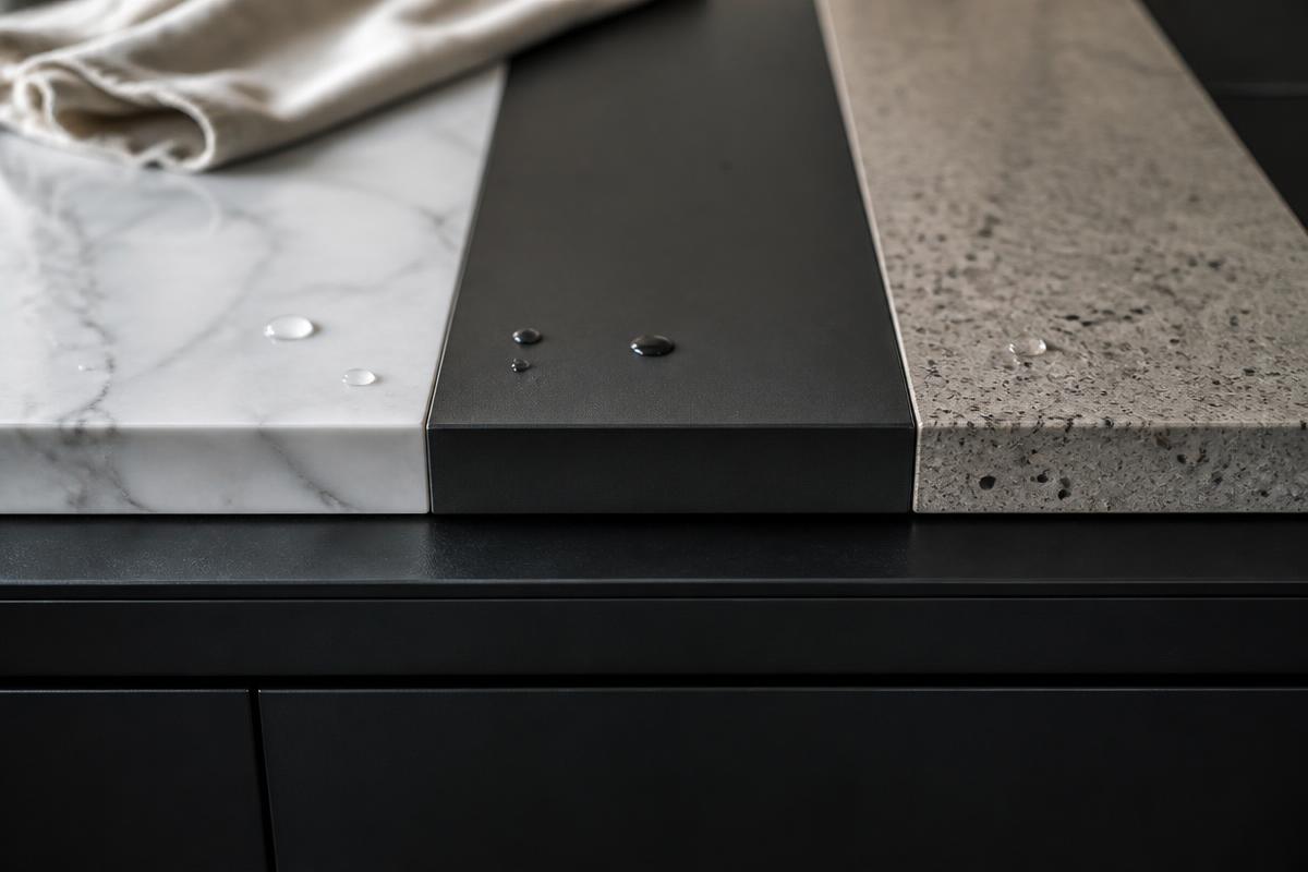Detail van marmer, keramiek en composiet stalen op een matzwart front